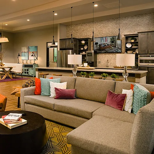 Inviting open-concept living room with cozy sectional, vibrant pillows, modern kitchen, and elegant decor touches.