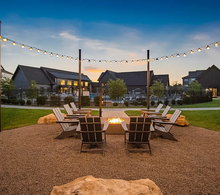 Charming outdoor seating area with elegant string lights and a cozy fire pit, perfect for serene evenings.