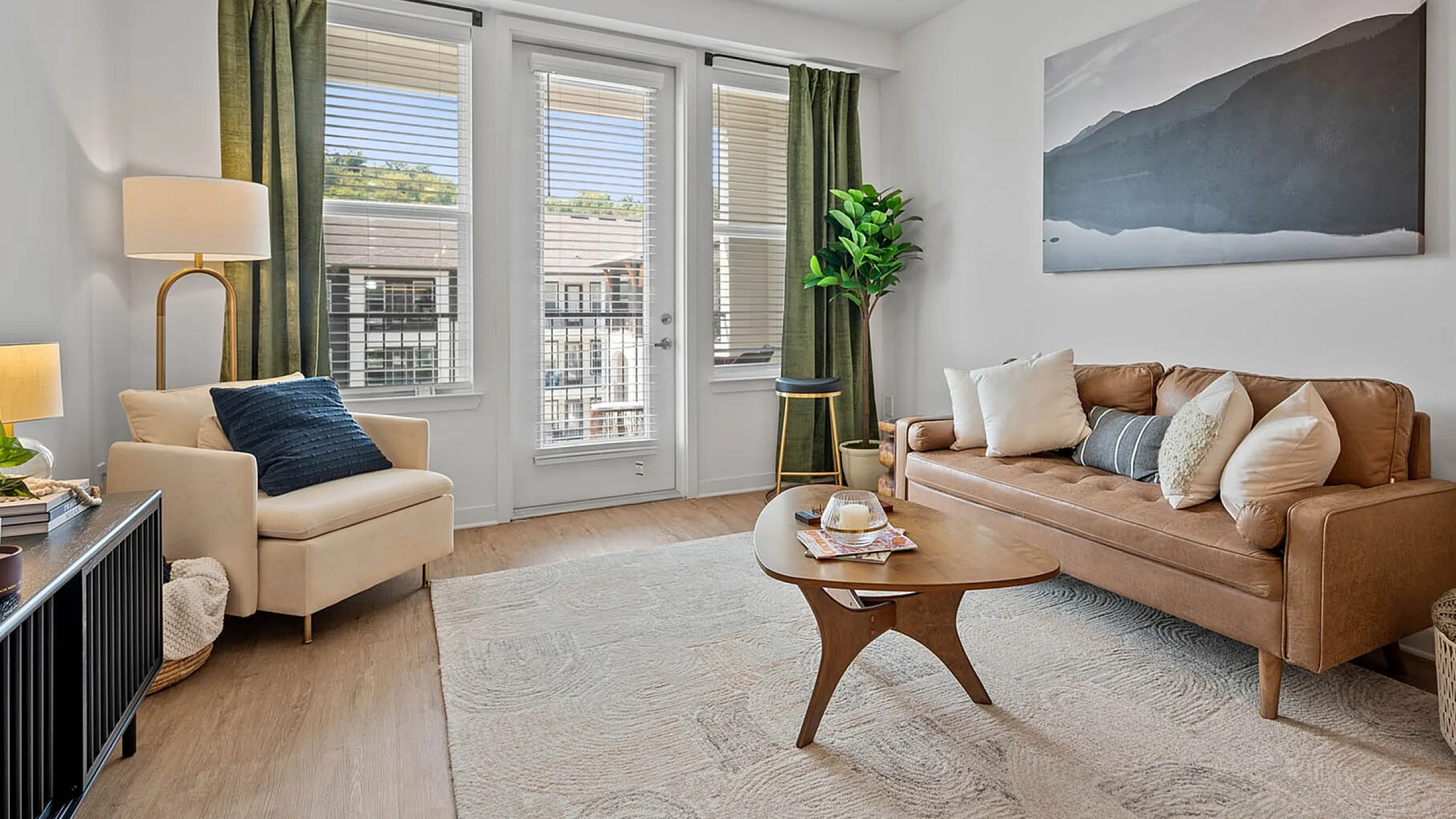 Chic living room with modern decor, featuring a cozy sofa, stylish armchair, and large windows offering abundant natural light.