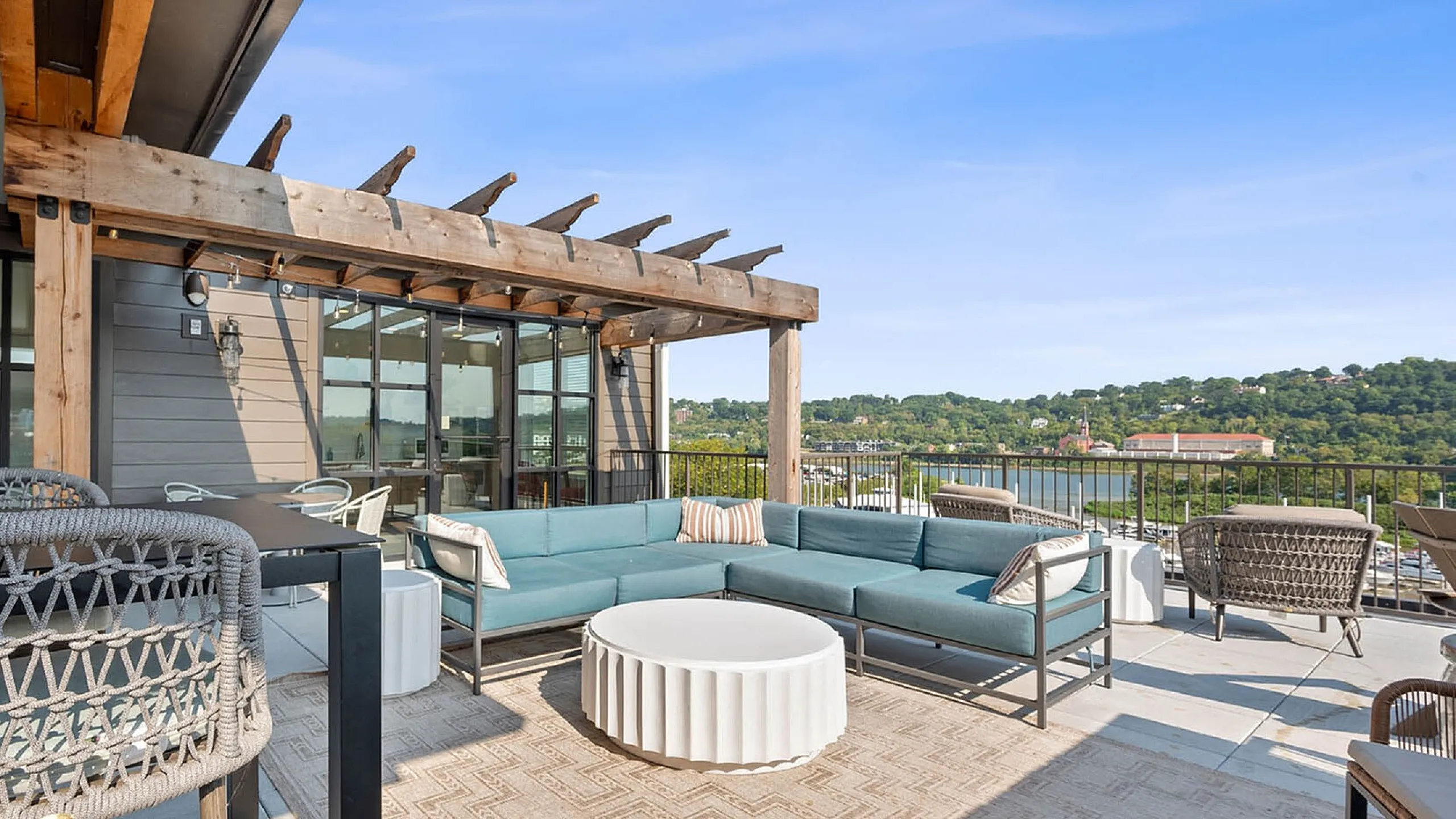 Luxurious outdoor terrace with chic wicker furniture, overlooking serene greenery and cityscape. Perfect for relaxation and entertaining.