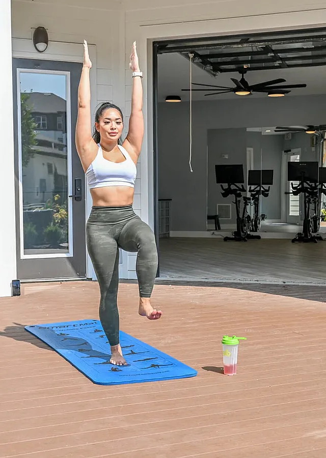 Vibrant outdoor yoga session on a sunny terrace with an inviting fitness studio in the background, perfect for maintaining an active lifestyle.