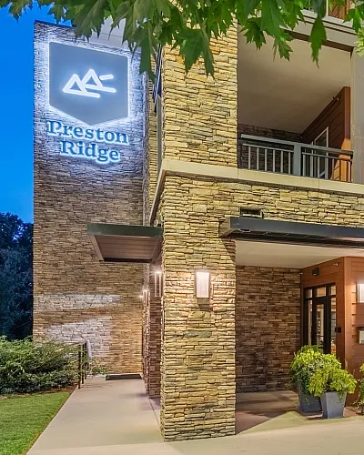 Charming apartment entrance with stone facade, modern lighting, and lush greenery.