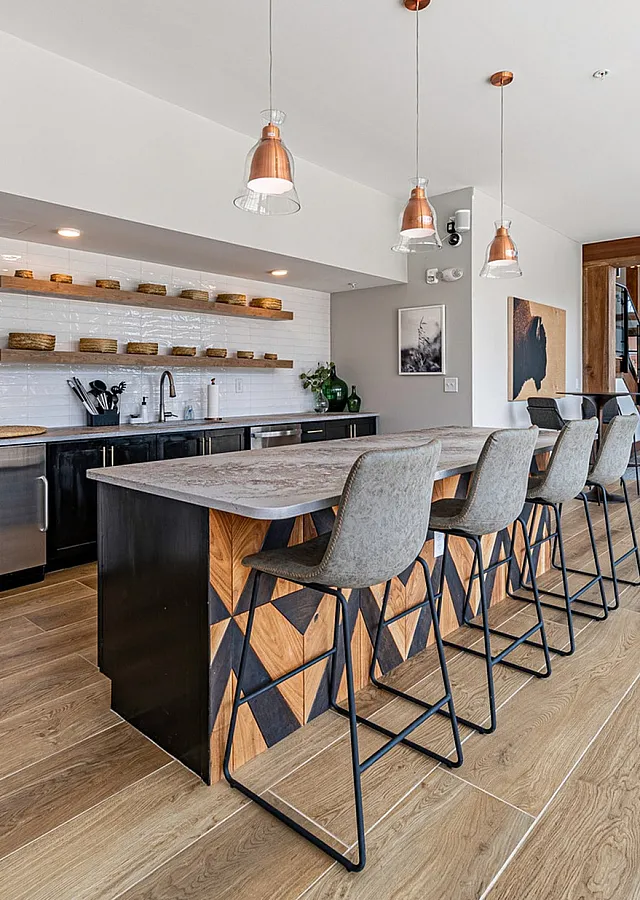 Modern open-concept kitchen with sleek stainless steel appliances, stylish pendant lighting, and a spacious island with chic bar seating overlooking a cozy living area.