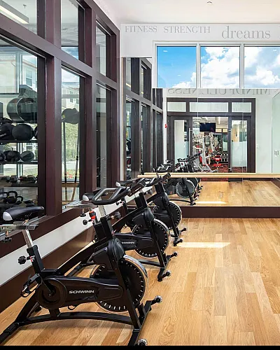 Modern fitness studio featuring sleek exercise bikes, mirrored walls, and natural light, offering a vibrant workout environment.