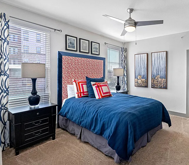 Vibrant bedroom featuring modern decor, a plush blue bed, stylish artwork, and ample natural light.