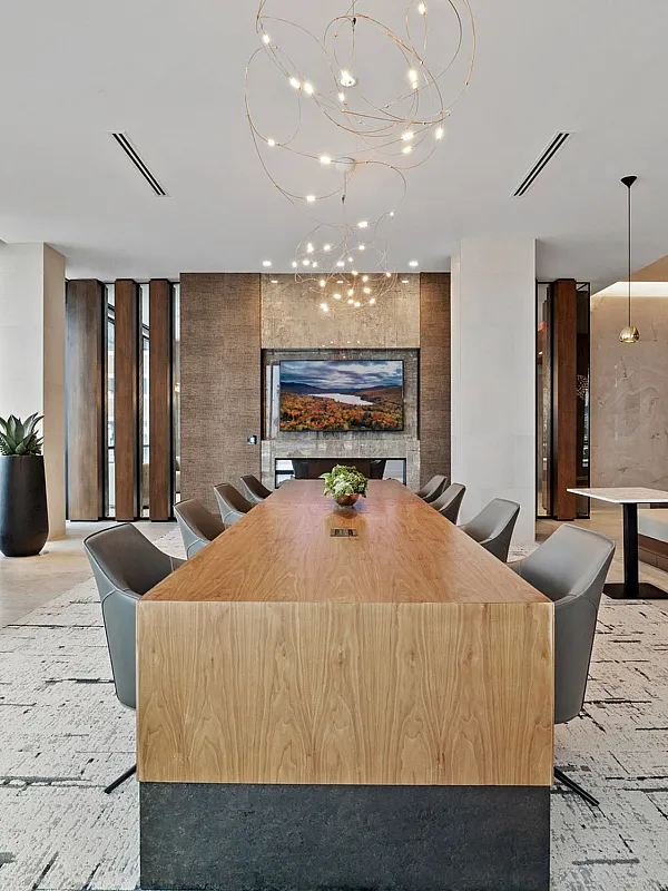 Modern dining area featuring a sleek wooden table, elegant pendant lighting, and stylish seating in a luxurious open-concept space.