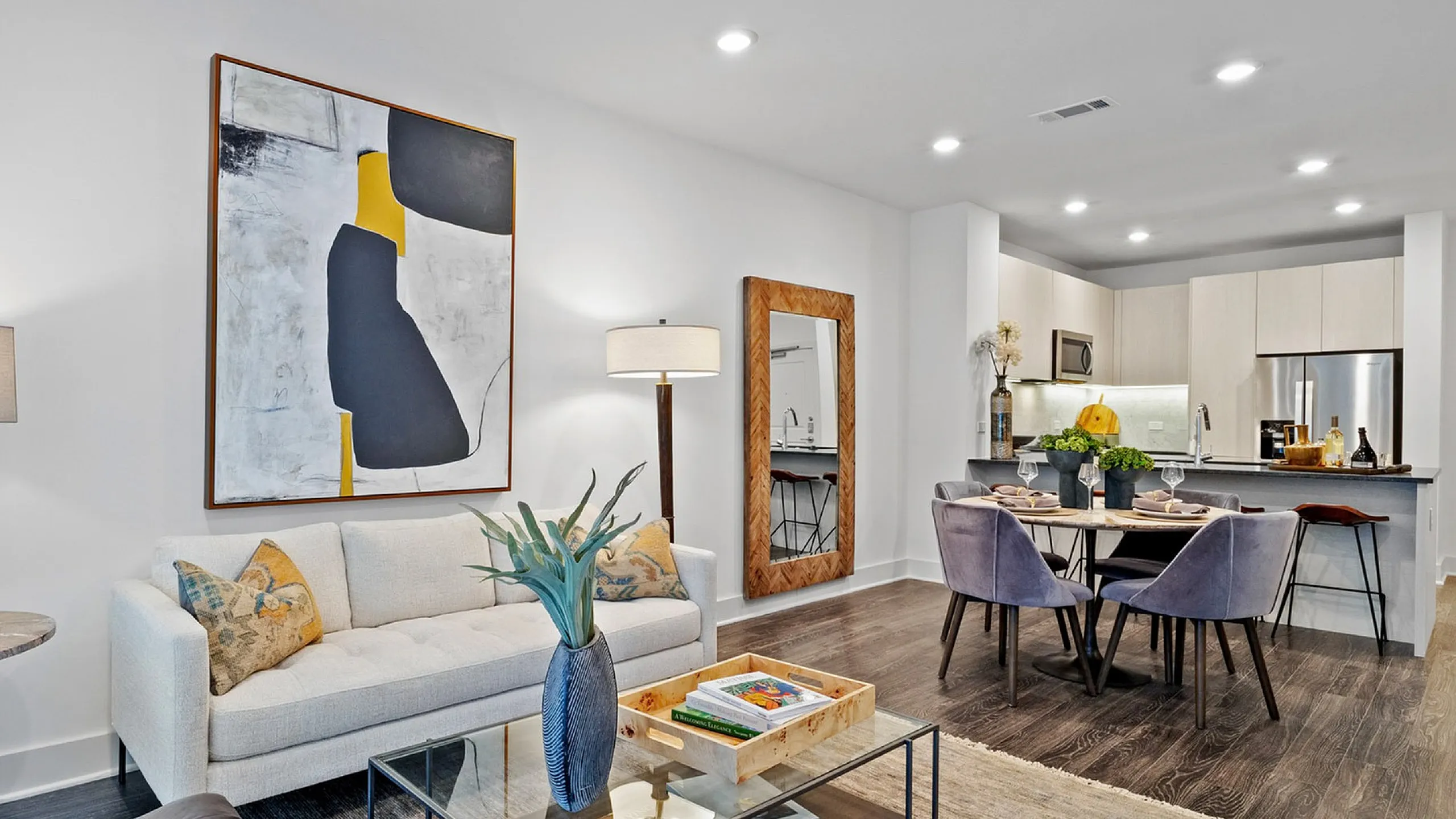 Modern open-concept living space featuring a chic living room, dining area, and stylish kitchen with elegant decor and contemporary artwork.