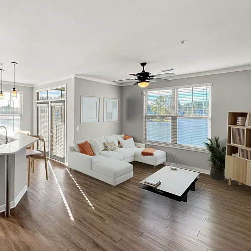 Bright, open-concept living space featuring a modern kitchen with stainless steel appliances, elegant hardwood floors, and a cozy seating area with abundant natural light and serene views.