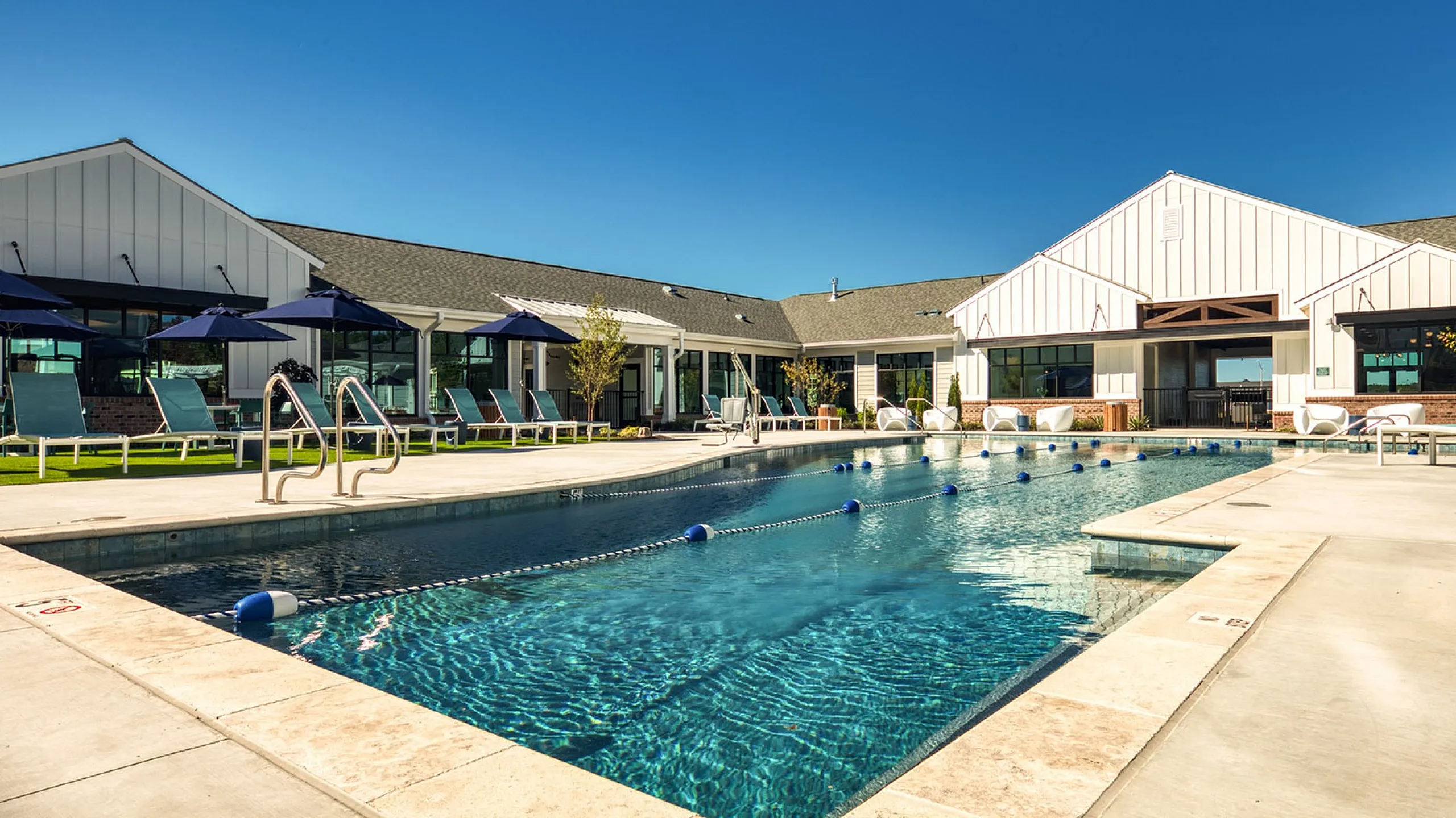 Luxurious outdoor pool area with sleek lounge chairs and vibrant umbrellas, perfect for relaxation and recreation.