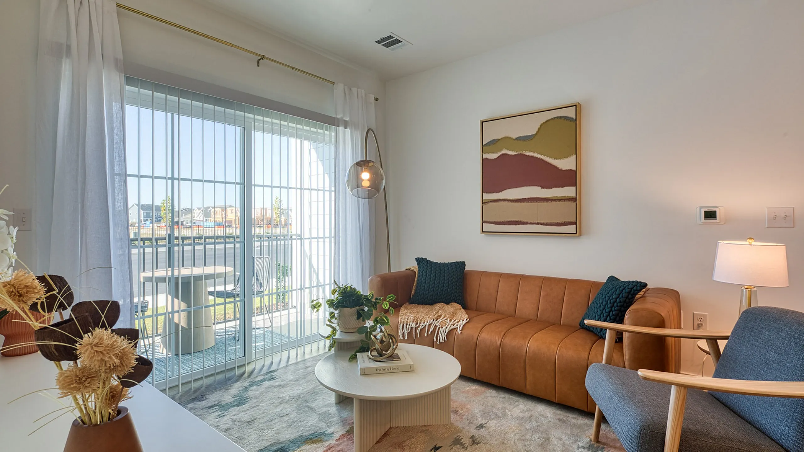 Bright and inviting living room featuring a stylish leather sofa, cozy armchair, and modern decor with ample natural light filtering through large sliding doors.