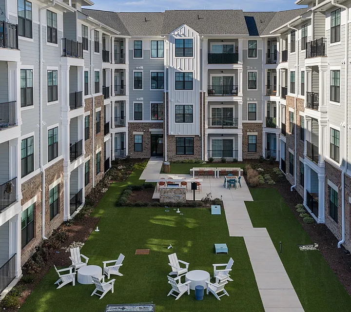Charming apartment courtyard with modern architecture, featuring balconies, manicured lawns, and inviting outdoor seating areas.