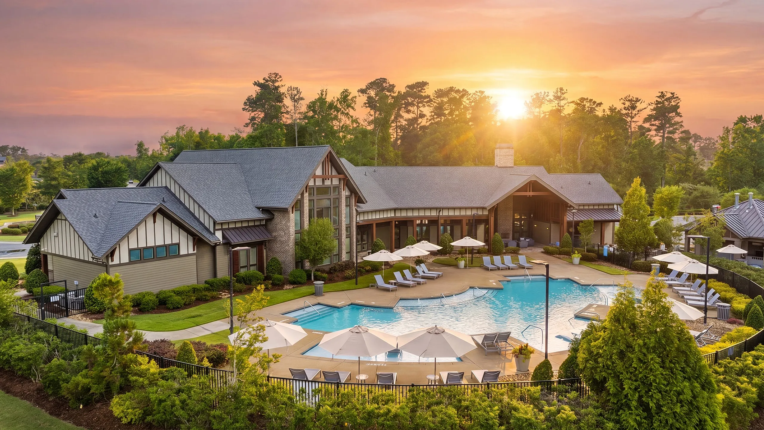 Luxurious residential clubhouse with a sparkling pool, surrounded by lush greenery and set against a stunning sunset backdrop.