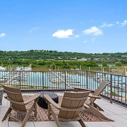Stunning apartment balcony overlooking a serene marina with lush greenery and a vibrant sky, perfect for relaxation and outdoor leisure.