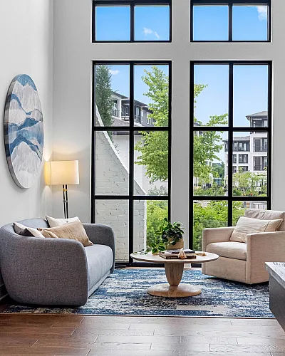 Contemporary living space with high ceilings, elegant windows, and cozy seating, offering a bright and inviting atmosphere.