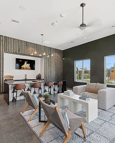 Modern lounge area with sleek bar counter, stylish seating, and a wall-mounted fireplace, perfect for relaxation and entertainment.