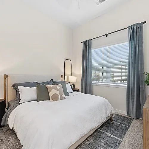 Bright and cozy bedroom with elegant decor, featuring a plush bed, modern lighting, and large window with stylish curtains.