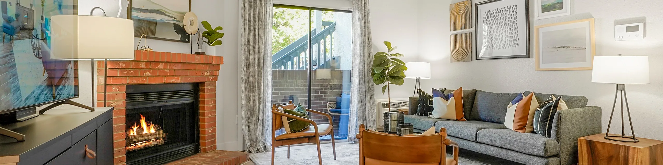 Charming living room with cozy brick fireplace, modern decor, and inviting natural light through glass doors.
