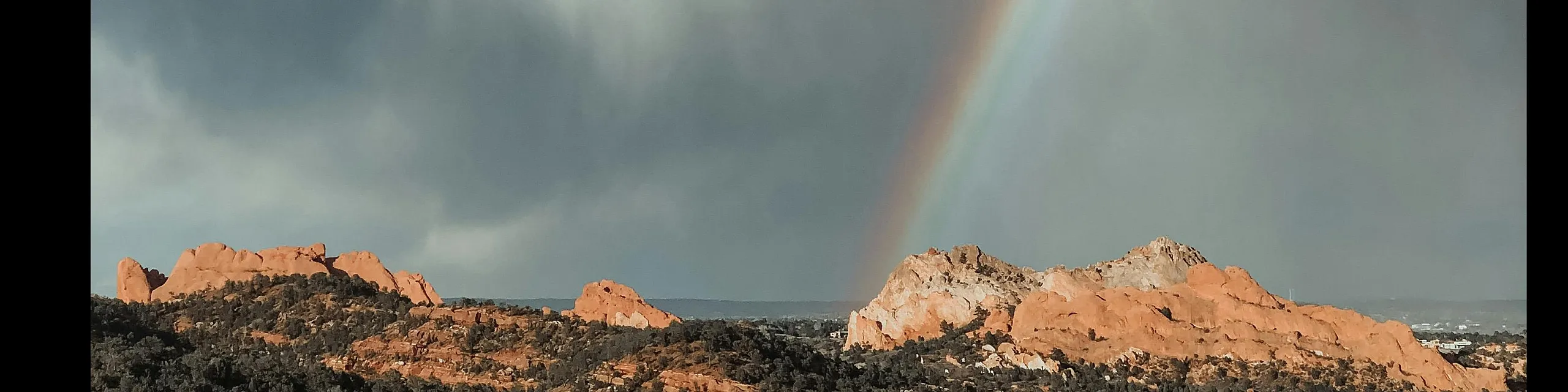 Breathtaking desert landscape with majestic rock formations and a vibrant rainbow arcing across dramatic skies.