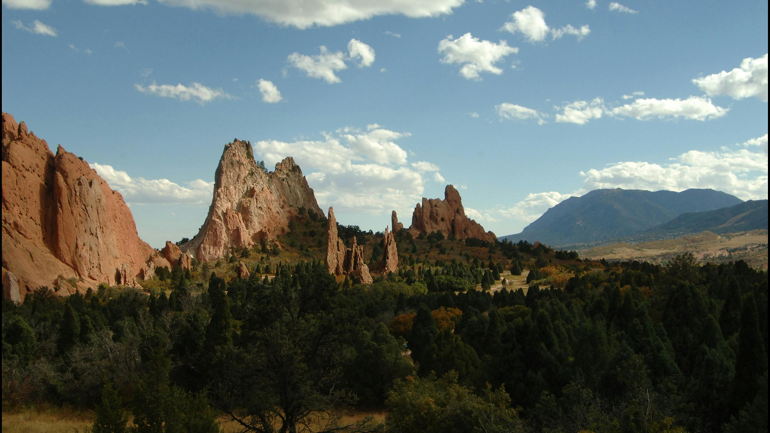 Breathtaking landscape of majestic red rock formations against a backdrop of a vibrant blue sky with scattered clouds.