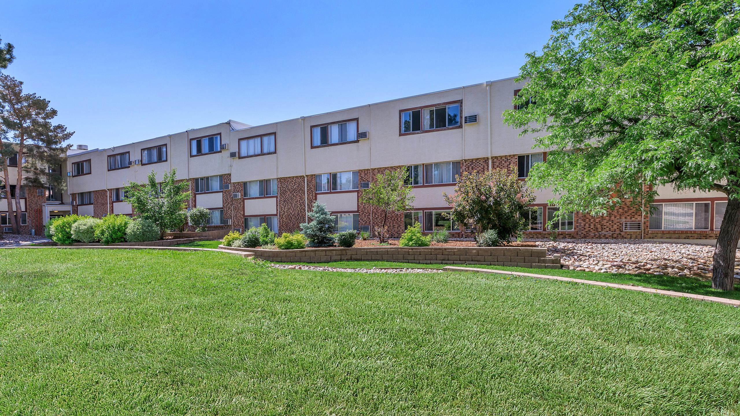 Charming apartment complex with lush green lawns and mature trees, perfect for serene living.