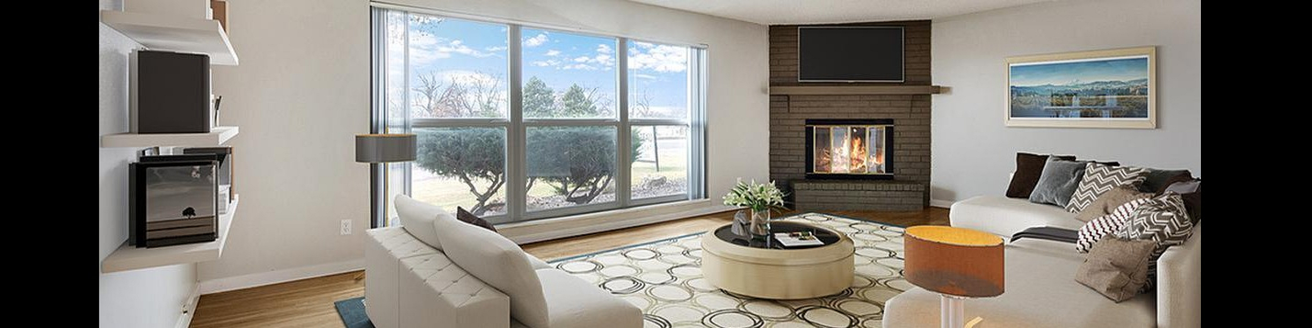 Inviting living room with large windows, a cozy fireplace, modern decor, and stylish couches offering a tranquil view.