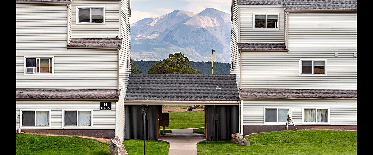 Charming apartment complex with picturesque mountain views, nestled in a serene suburban setting with lush green lawns.