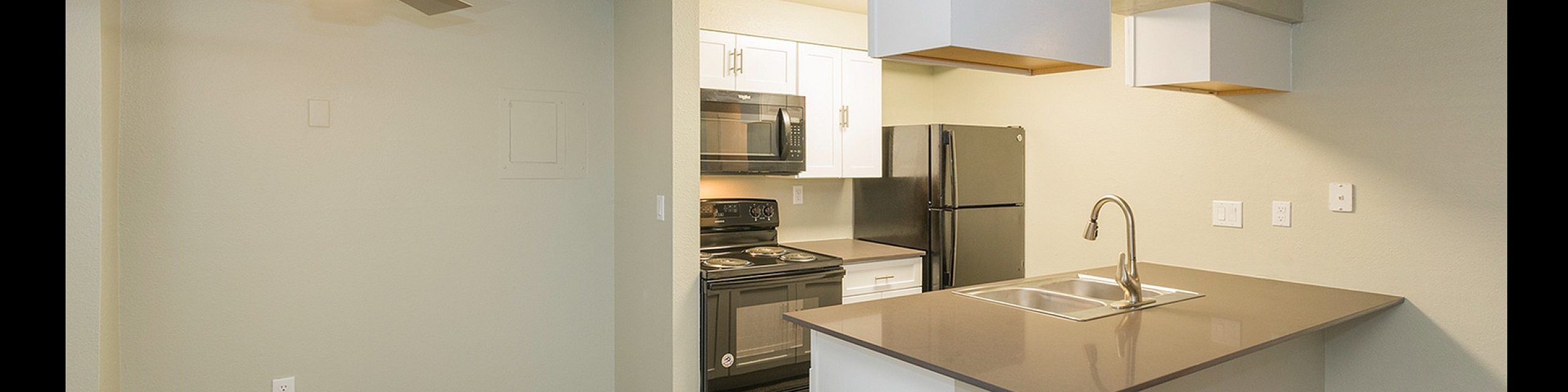Bright modern apartment kitchen with sleek cabinetry, stainless steel appliances, and elegant wood flooring.