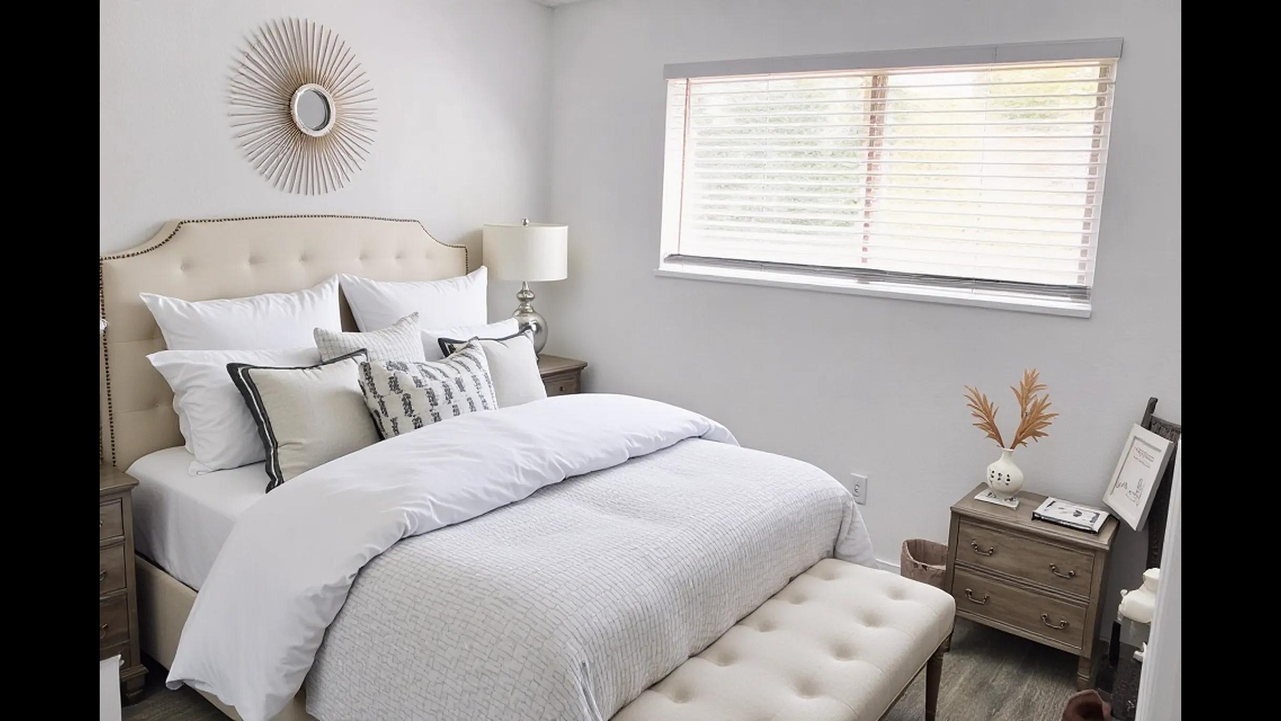 Bright and inviting bedroom with a plush, luxurious bed, elegant decor, and ample natural light from a large window.