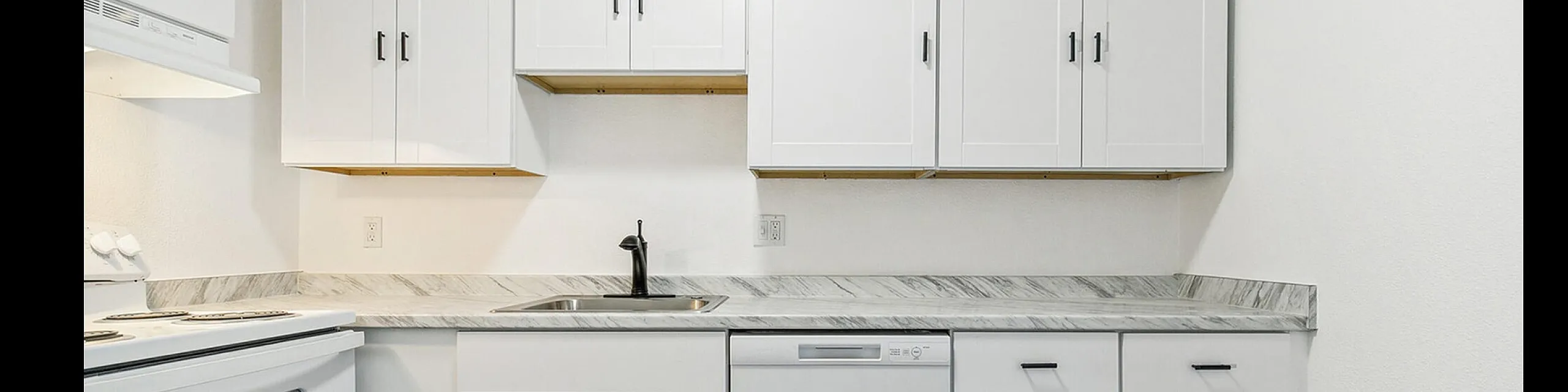 Modern kitchen with sleek white cabinetry, marble countertops, and stainless steel appliances, featuring ample storage and a clean, elegant design.