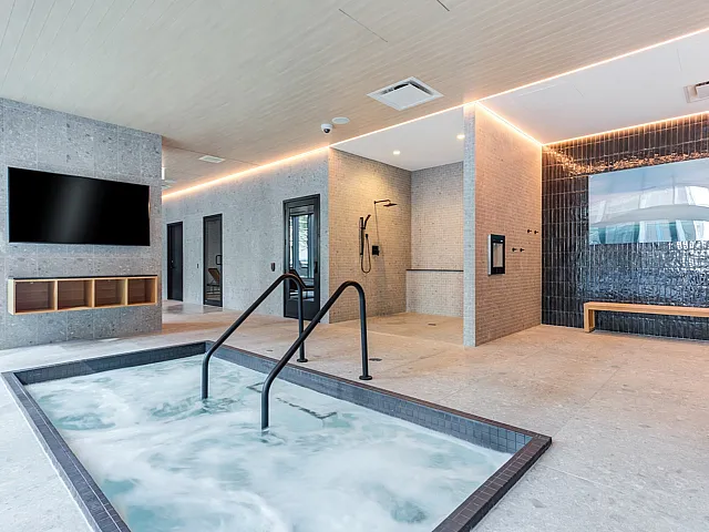 Luxury apartment complex spa area with hot tub and contemporary shower space.