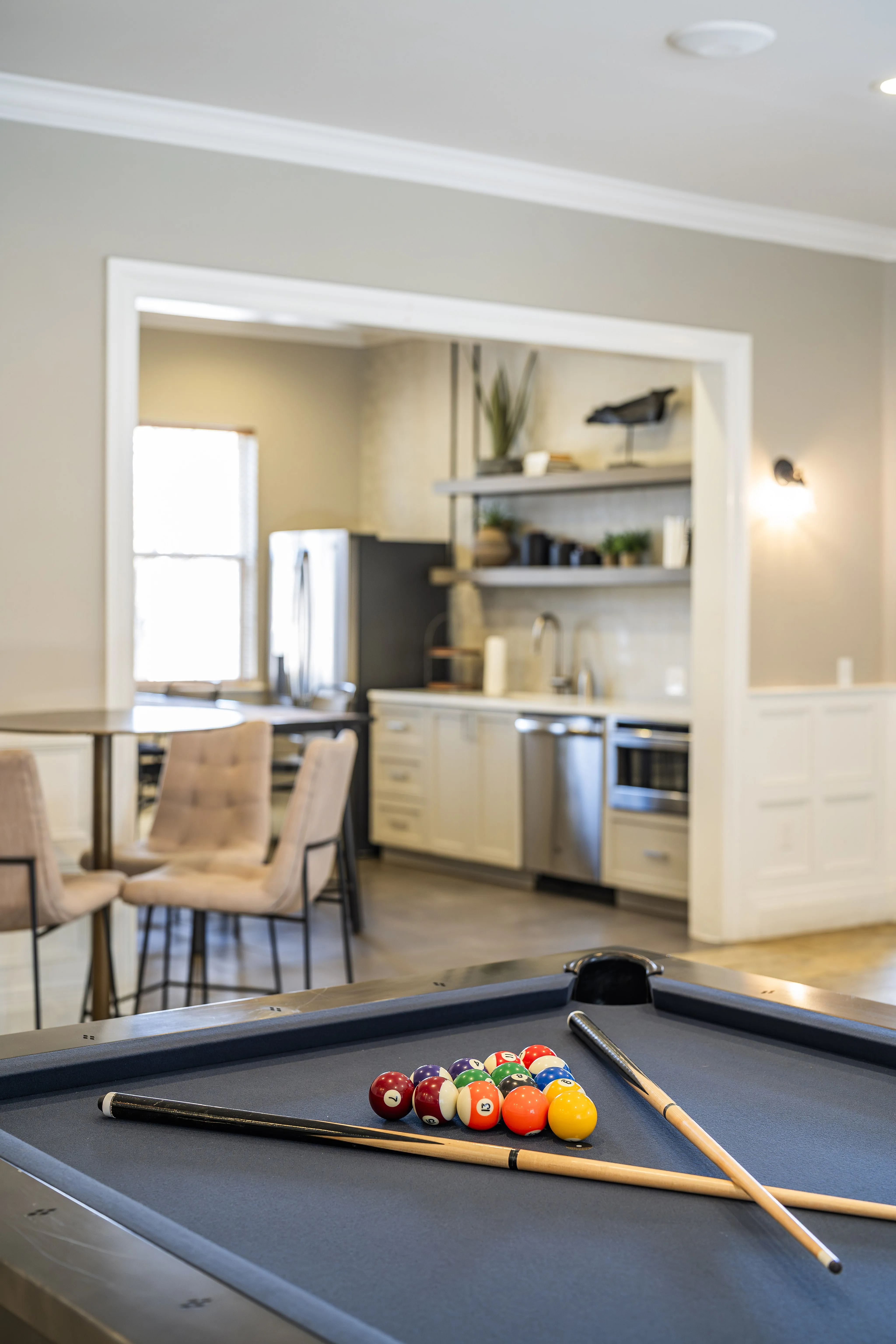 Modern apartment featuring an elegant open-concept kitchen with stainless steel appliances, stylish dining area, and an inviting billiard table perfect for entertaining.