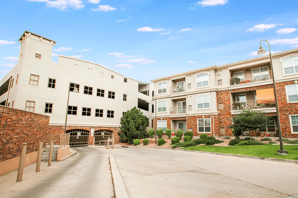 Charming apartment complex exterior with modern architecture, lush landscaping, and sunlit pathways.