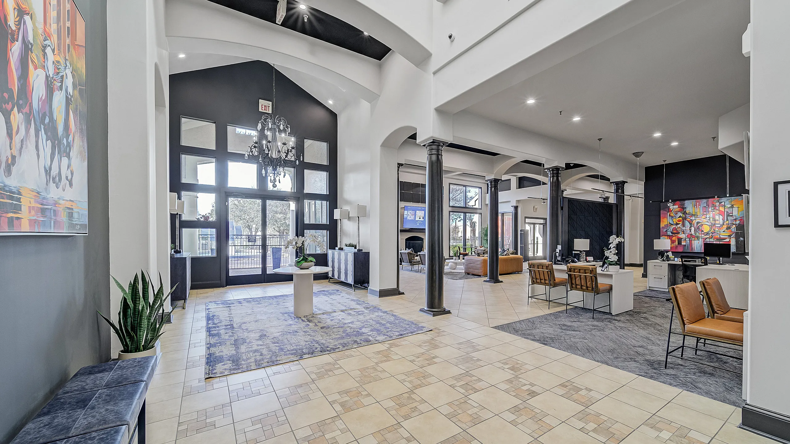Elegant apartment lobby with high ceilings, stylish chandeliers, modern furniture, and vibrant artwork creating a welcoming and luxurious atmosphere.