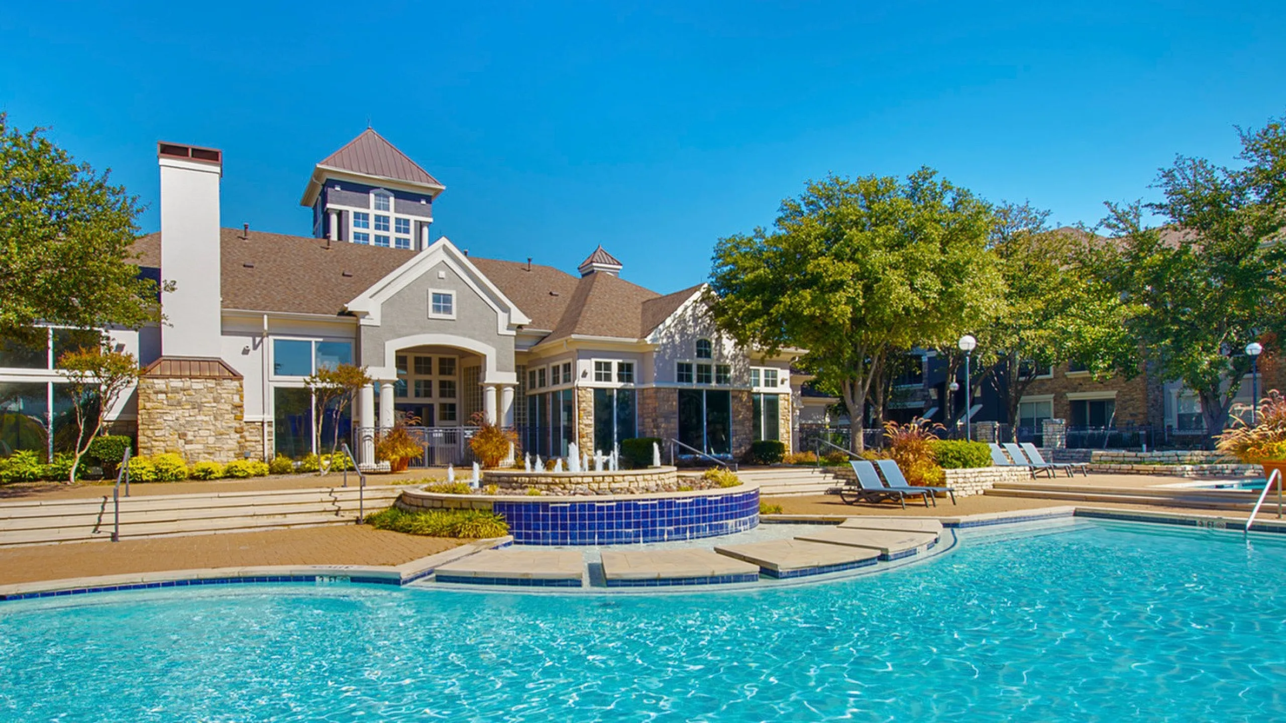 Luxurious apartment complex with sparkling swimming pool, elegant architecture, and lush greenery, perfect for a serene lifestyle.