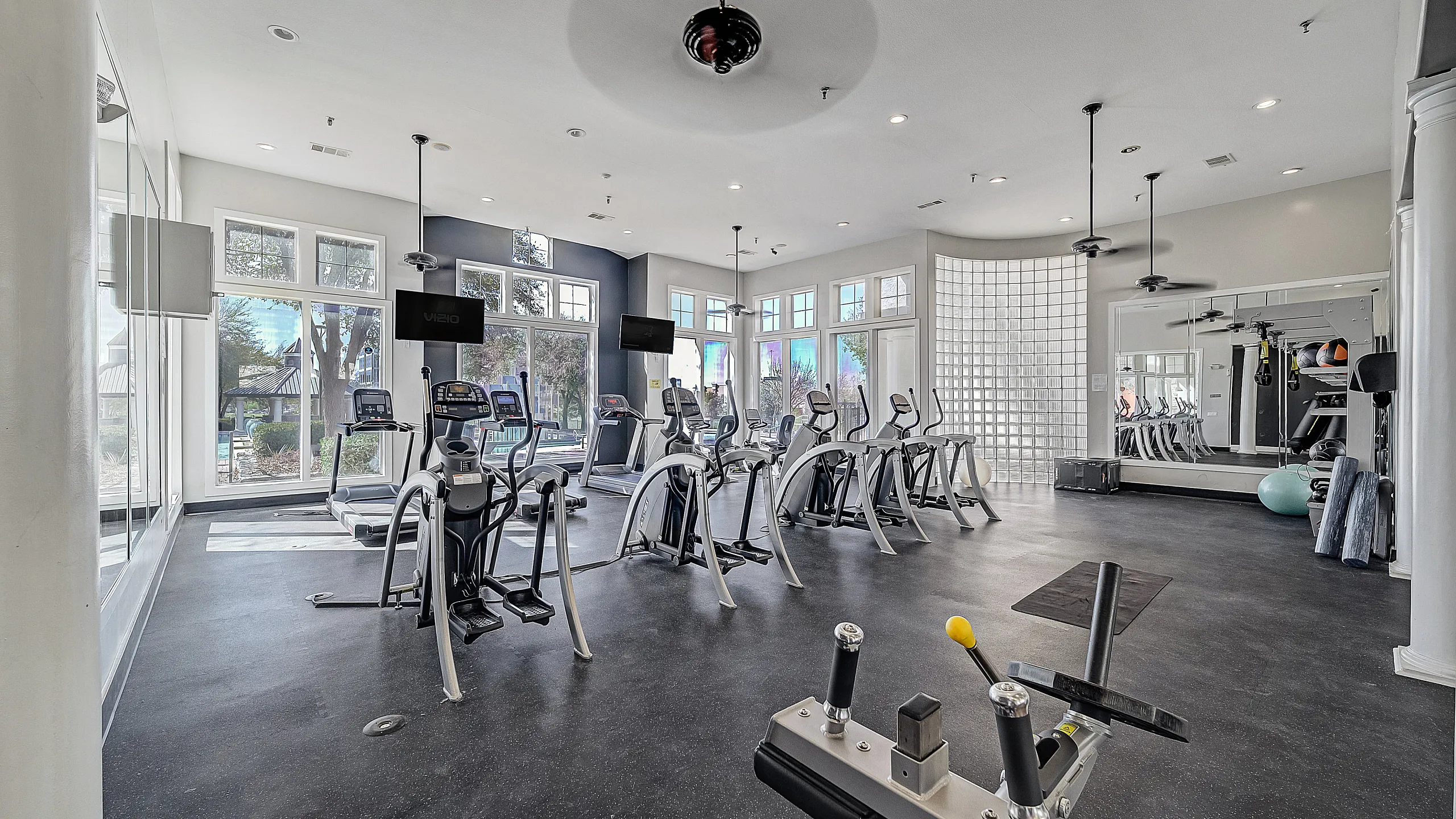 Modern fitness center with state-of-the-art exercise machines, large windows for natural light, and sleek design.