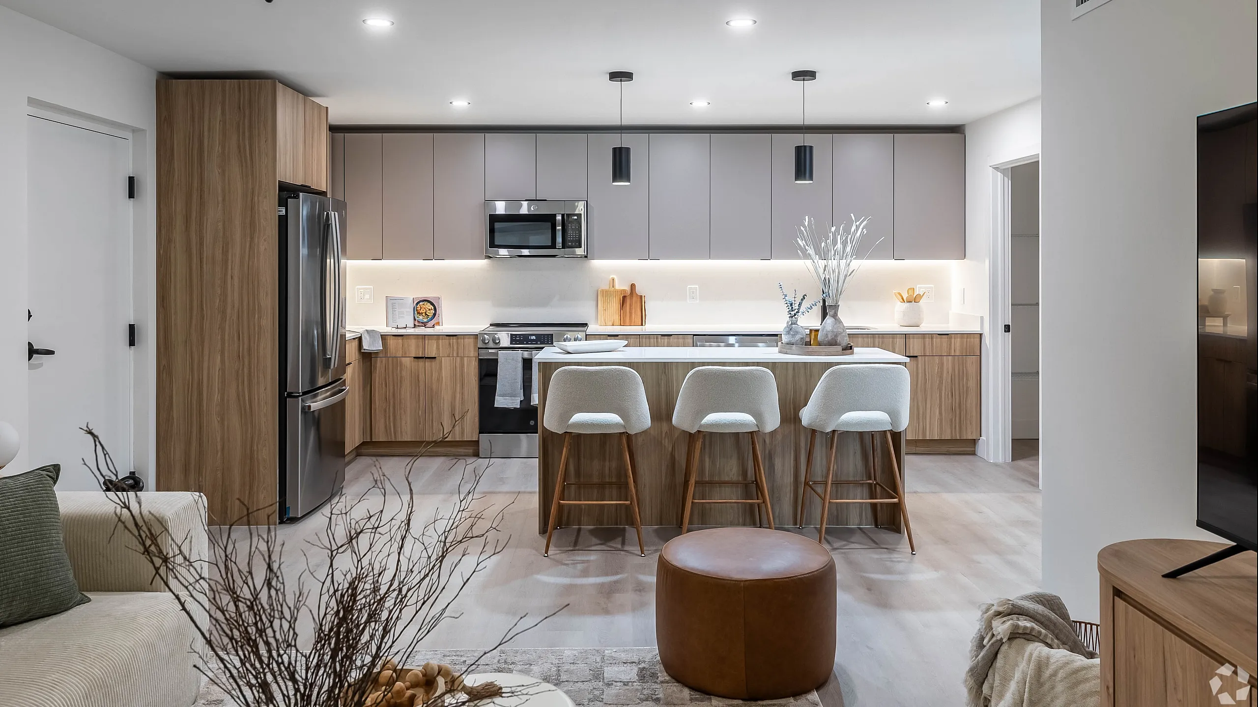 Elegant modern kitchen with sleek cabinetry, stylish pendant lighting, and a spacious island with seating for three, offering a blend of functionality and contemporary design.