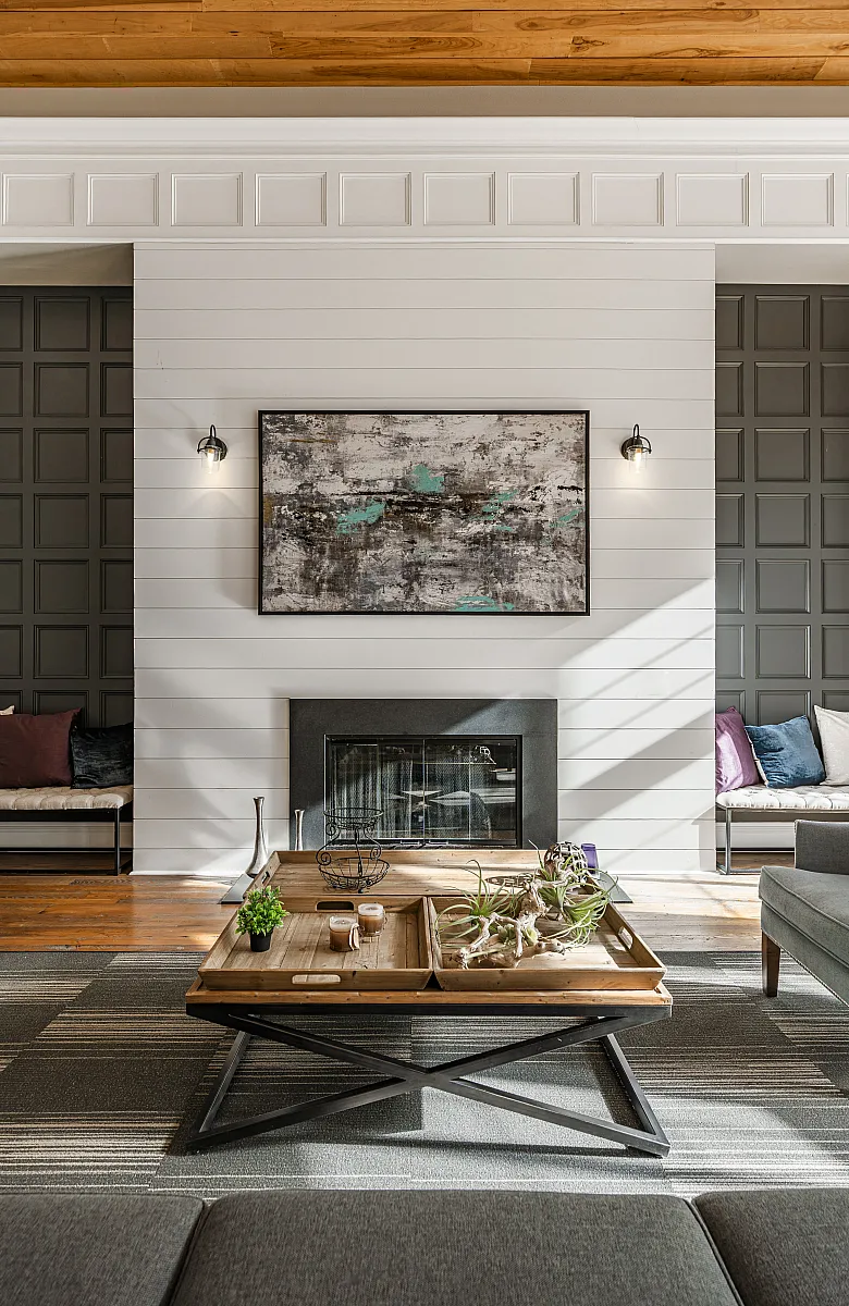 Inviting living room with elegant modern d&eacute;cor, featuring a cozy fireplace, stylish wall art, and a chic wooden coffee table bathed in natural light.