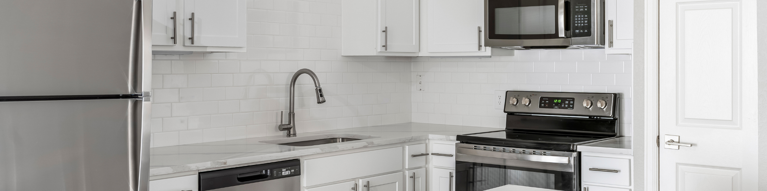 Contemporary kitchen with stainless steel appliances, sleek white cabinets, and a modern faucet.