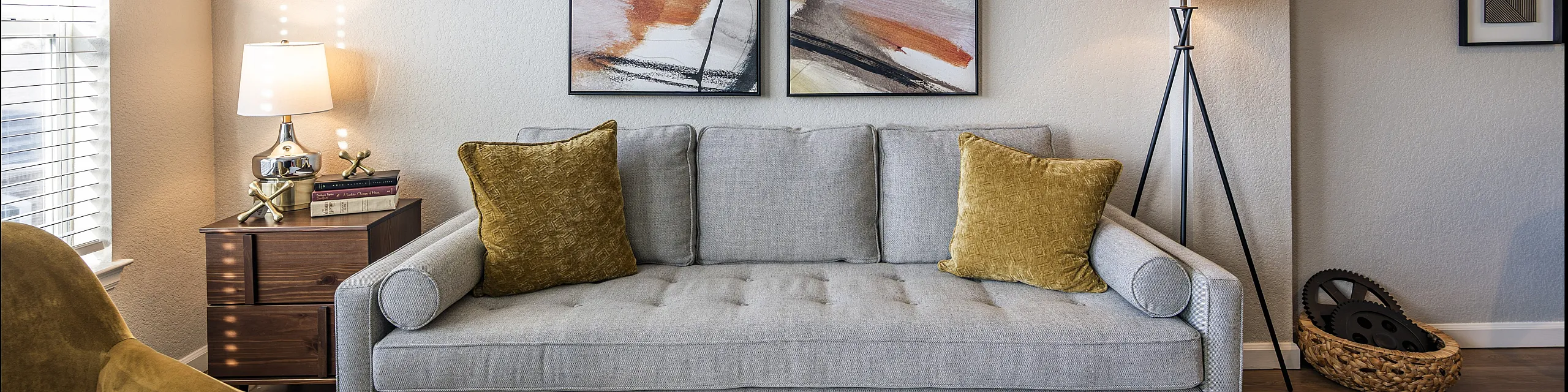 Chic living room with stylish gray sofa, abstract wall art, and contemporary lighting, perfect for cozy relaxation.
