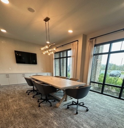 Sophisticated conference room with a large wooden table, contemporary lighting, and floor-to-ceiling windows.