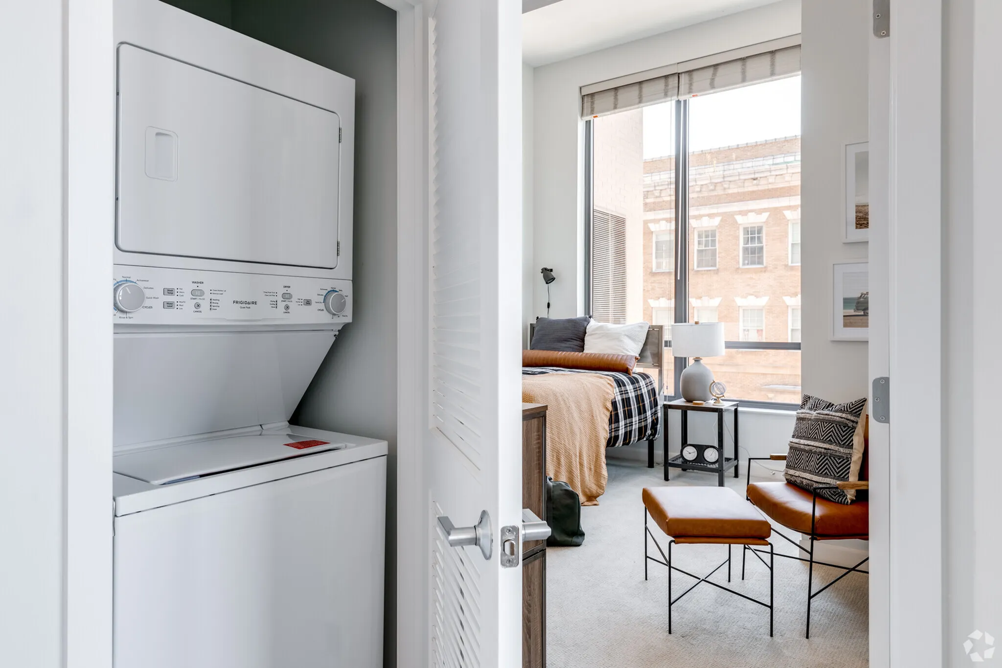 Bright apartment featuring in-unit laundry and a cozy bedroom with modern furnishings and large windows.