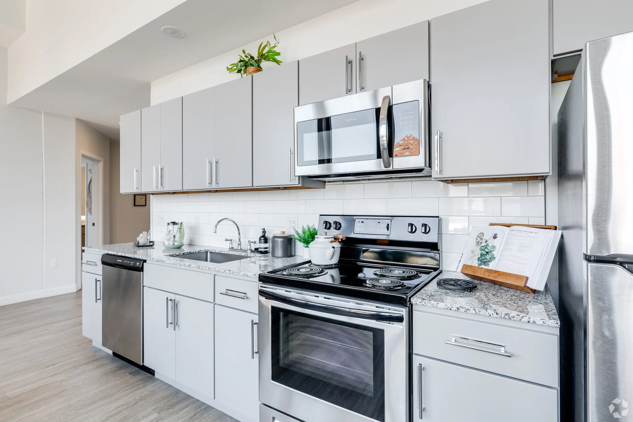 Sleek modern kitchen featuring stainless steel appliances, elegant gray cabinetry, and a stylish granite countertop with ample natural light.