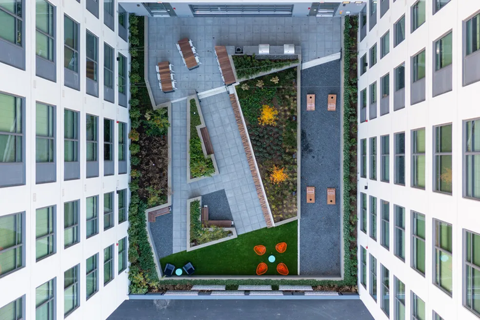 Stunning aerial view of a modern courtyard featuring lush greenery, sleek pathways, and stylish outdoor seating in a contemporary apartment complex.