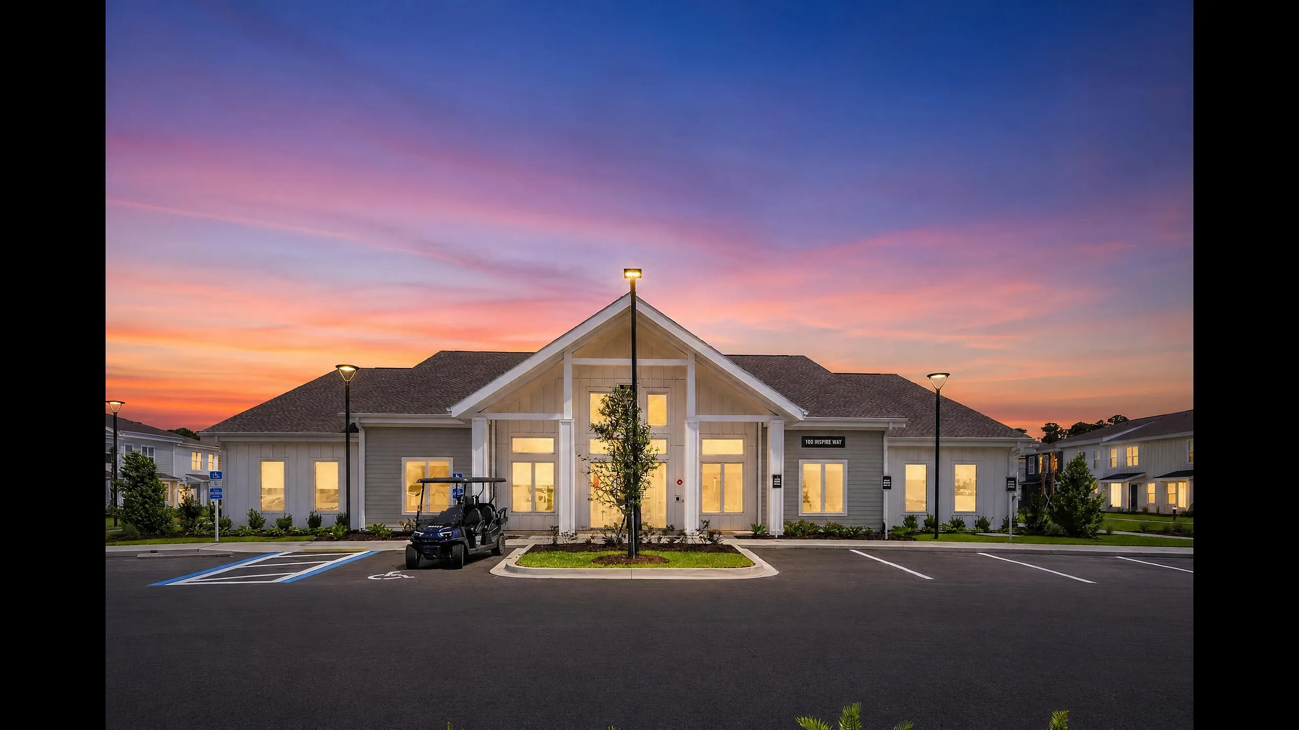 Charming modern building with inviting entrance, set against a stunning sunset sky, highlighting a serene and stylish community space.