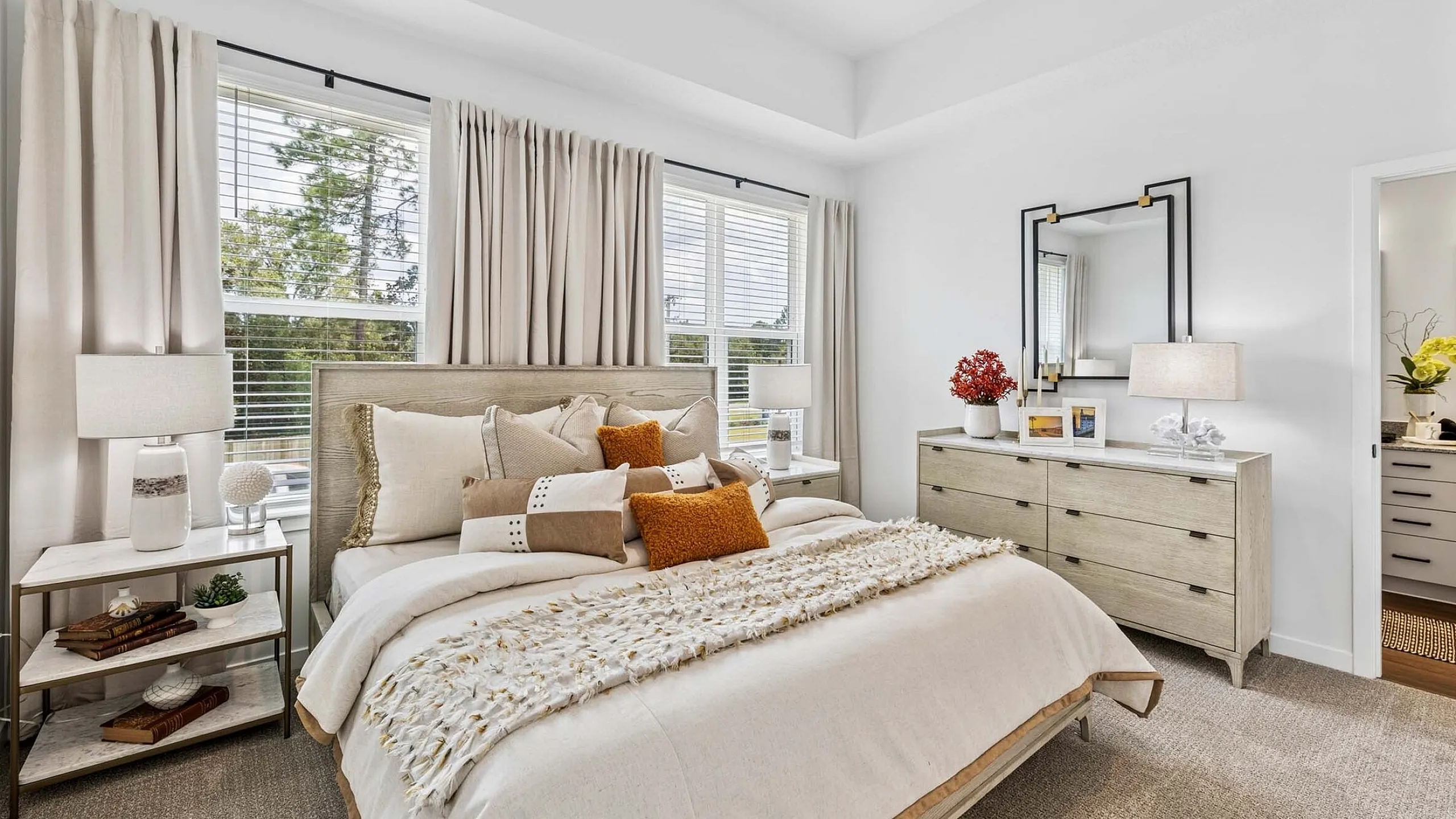 Chic and cozy bedroom with plush bedding, elegant decor, and abundant natural light from large windows.