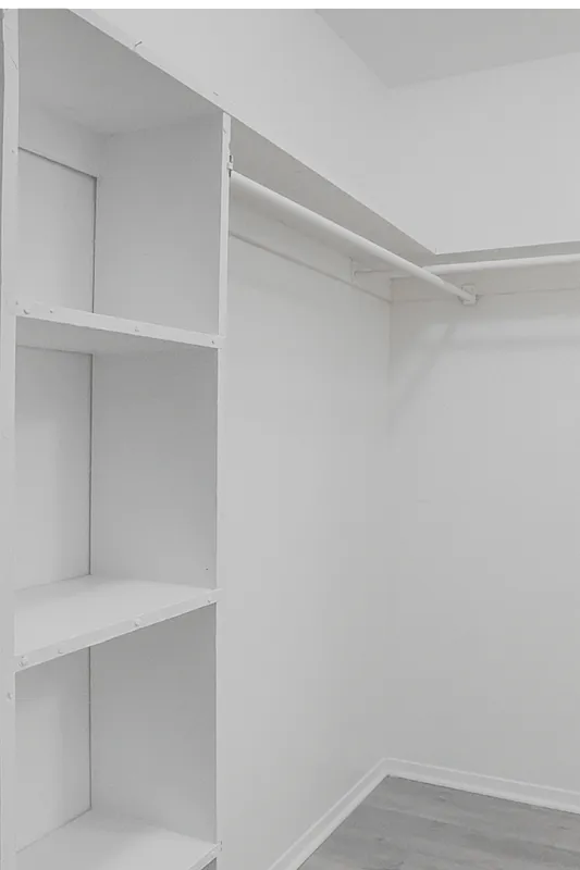Spacious walk-in closet with built-in shelving and ample hanging space, perfect for organized living.