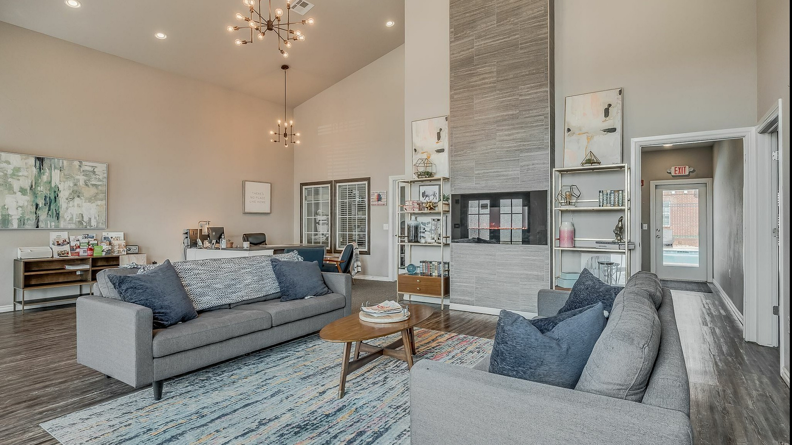 Elegant living area with modern decor, featuring plush grey sofas, artistic lighting, and a cozy fireplace, perfect for relaxation and entertaining.