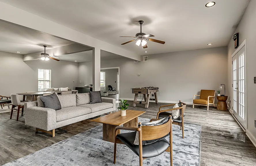 Spacious open-plan living area boasting modern furniture, elegant wood flooring, and abundant natural light.