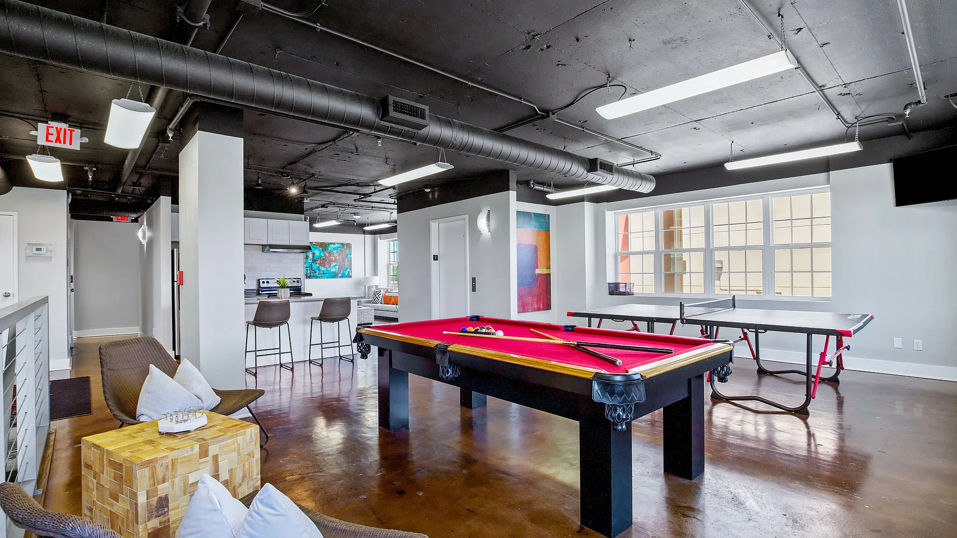 Modern loft-style apartment with open space featuring a pool table, ping pong table, and stylish kitchen with bar seating. Ideal for entertaining.