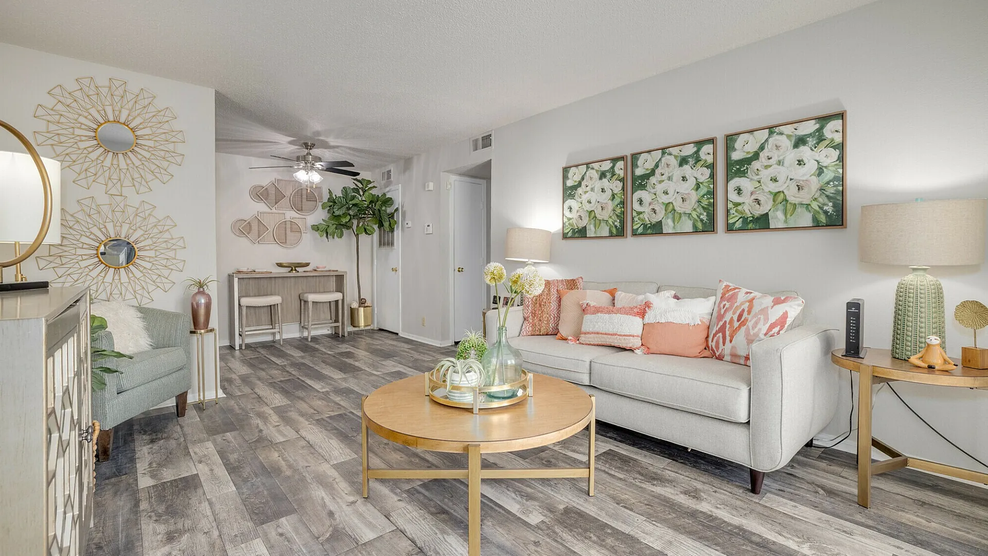 Modern living room with elegant decor, featuring a plush sofa adorned with colorful throw pillows, stylish wall art, and sleek wooden flooring.